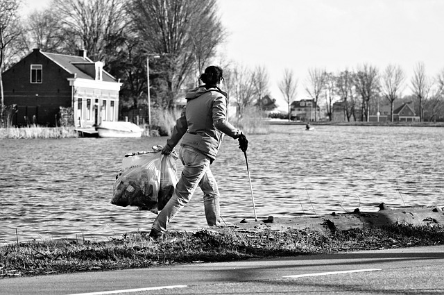 B&W person picking up litter