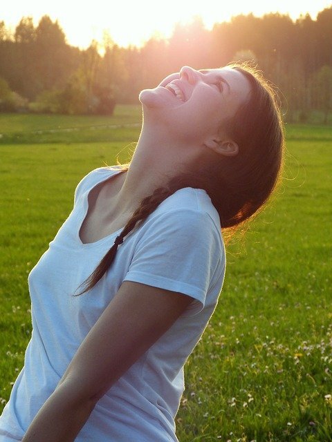 Girl in white t-shirt stretching in a meadow